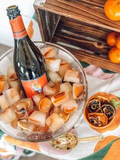 a glass bowl filled with ice cubes next to an orange and bottle of wine