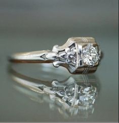 an antique diamond engagement ring on a reflective surface