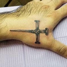 a hand with a cross tattoo on it and a knife in the middle of it