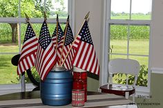 several american flags are placed on top of a blue barrel in the middle of a room