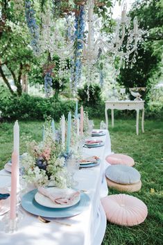 a table set up with plates and candles for an outdoor dinner in the park or garden