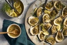 a platter filled with oysters next to a bowl of dipping sauce and spoon