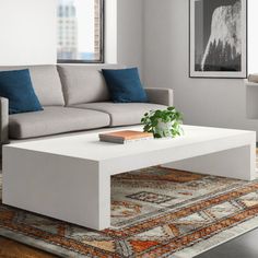 a white coffee table sitting on top of a rug in a living room next to a couch