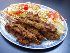 meat skewers and vegetables on a blue and white plate