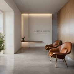 two brown chairs sitting next to each other in front of a wall with a sign on it