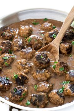 meatballs and gravy in a pot with a wooden spoon