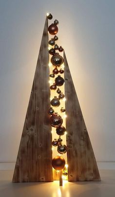 a christmas tree made out of wood with lights on it's sides and balls hanging from the top