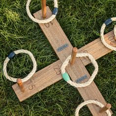 a cross made out of wood and rope with two rings on the end, sitting in grass