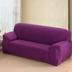 a green couch sitting on top of a hard wood floor next to a white table