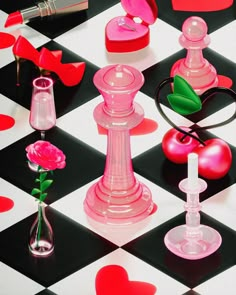 a chess board with pink and red accessories on it's surface, including a rose