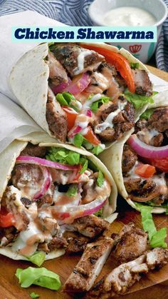 three pita sandwiches with meat and vegetables on a cutting board