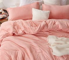 an unmade bed with pink sheets and pillows