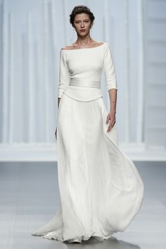 a woman walking down a runway wearing a white dress