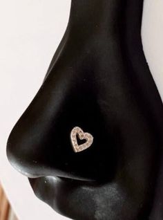 a black mannequin head with a heart shaped diamond ring on it's nose