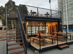 a house made out of shipping containers with stairs leading up to the second floor and an upper deck