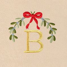 the letter b is decorated with red bows and green leaves, along with a gold monogrammed bow