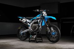 a blue and black dirt bike sitting on top of a stand in a garage area