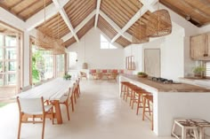 an open kitchen and dining room area with wood beams on the ceiling, white walls and flooring