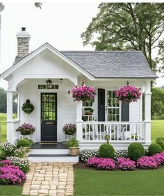 a small white house with pink flowers on the front porch