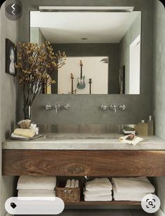 a bathroom sink sitting under a mirror next to a wooden shelf filled with folded towels