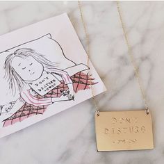 a gold necklace with the words don't disturb on it next to a card