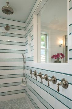 a bathroom with white and blue striped wallpaper on the walls, along with a walk in shower