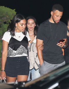 a group of people standing next to each other in front of a car at night