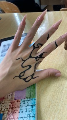 a person's hand with tattoos on it sitting at a wooden table next to a donut