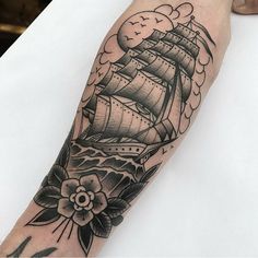 a black and white photo of a ship with flowers on it's arm tattoo