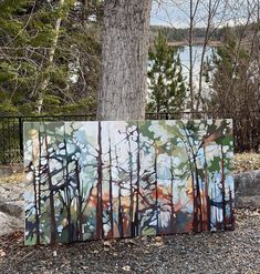 a painting is shown in front of a tree and some water with trees behind it