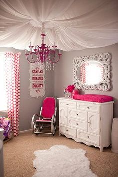 a pink and white baby's room with a chandelier