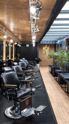 the interior of a hair salon with black chairs and wooden floors, mirrors on the wall