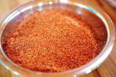 a glass bowl filled with red seasoning on top of a wooden table