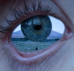 an eye looking into the distance with mountains in the background