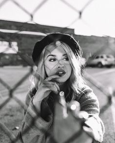 a black and white photo of a woman holding her finger up to her mouth while looking at the camera