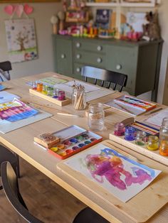 the table is set up with art supplies and watercolors on it for kids to paint