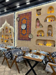 the interior of a restaurant with tables, chairs and rugs hanging on the wall