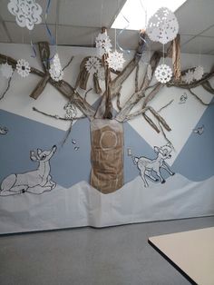 an office cubicle decorated with paper snowflakes, deer and tree branches hanging from the ceiling