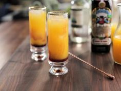 three glasses filled with orange juice on top of a wooden table