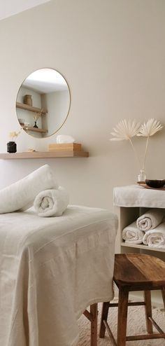 a bedroom with white linens on the bed, and a round mirror above it