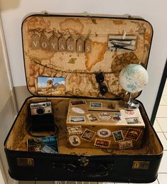 an open suitcase with various items inside it on the floor in front of a wall