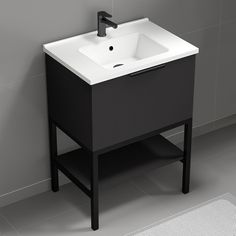 a white sink sitting on top of a black stand next to a gray tiled wall