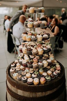 cupcakes are stacked on top of each other in front of a wine barrel