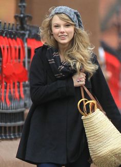 a woman is walking down the street with a basket in her hand and smiling at the camera