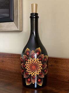 a black vase sitting on top of a wooden table next to a framed painting above it