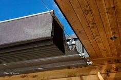 an awning is hanging from the side of a wooden building with a blue sky in the background