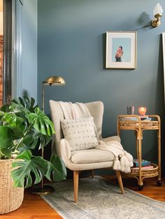 a living room with blue walls and a chair in front of a potted plant