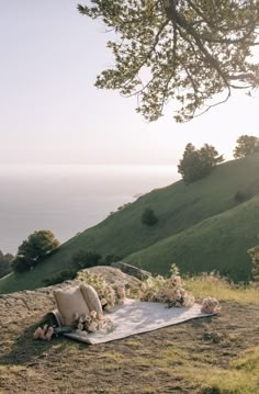 an outdoor seating area with flowers and greenery on the hillside overlooking the ocean in the distance