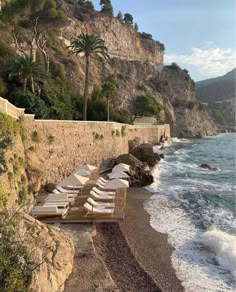 the beach is lined with lounge chairs and umbrellas near the water's edge