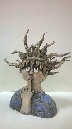 a sculpture of a man with branches on his head and hands under his chin, looking up at the viewer